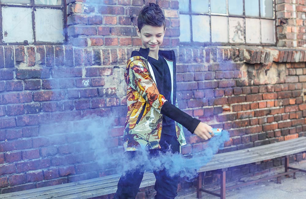 Boy in multi colour jacket with blue smoke