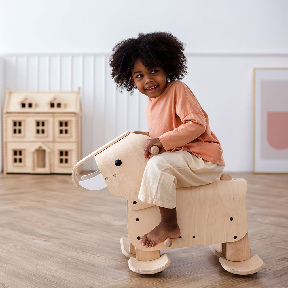 Young girl on PlanToys walking wooden elephant
