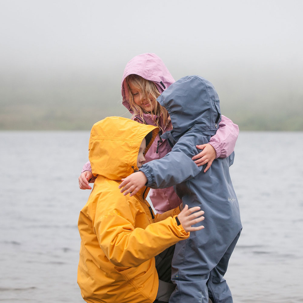 3 kids hugging wearing rain coats