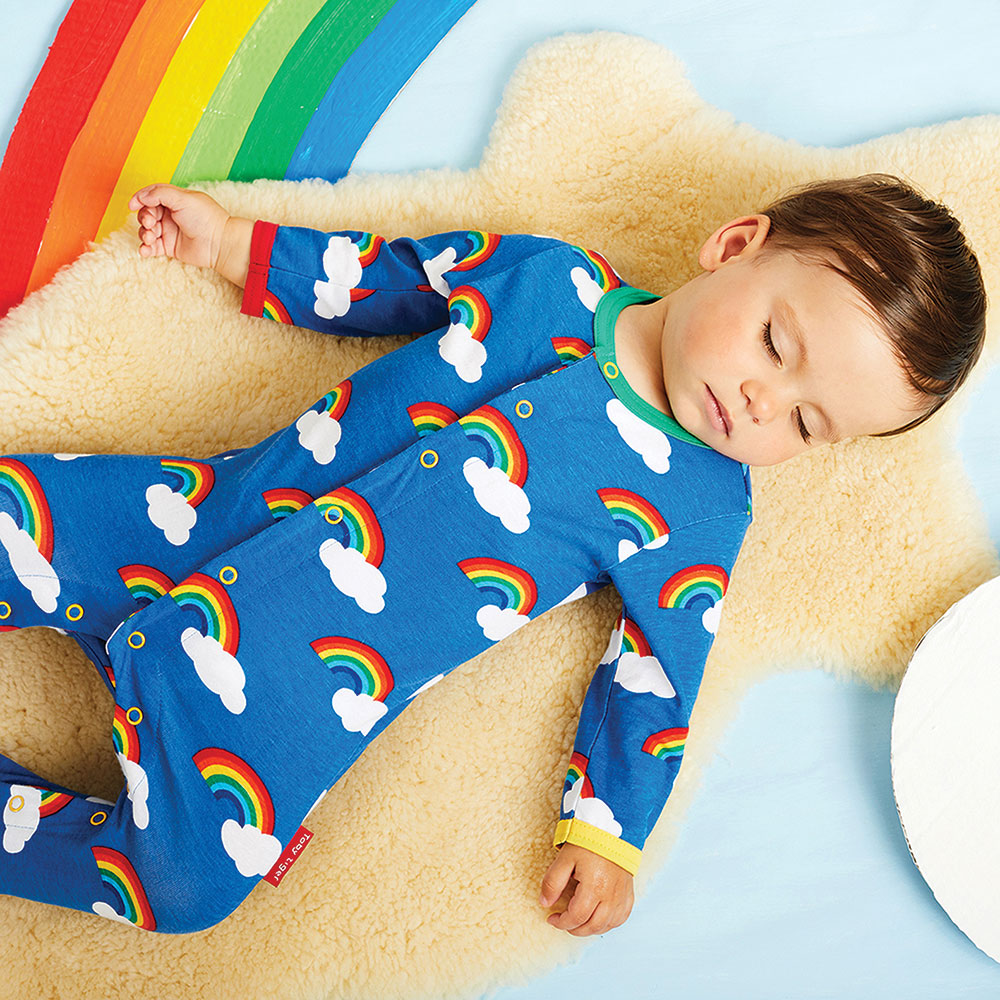 Young boy asleep in blue sleepsuit with rainbow print