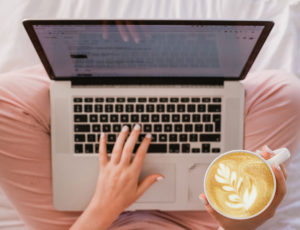 Lady sat on floor looking online holding a cup of coffee