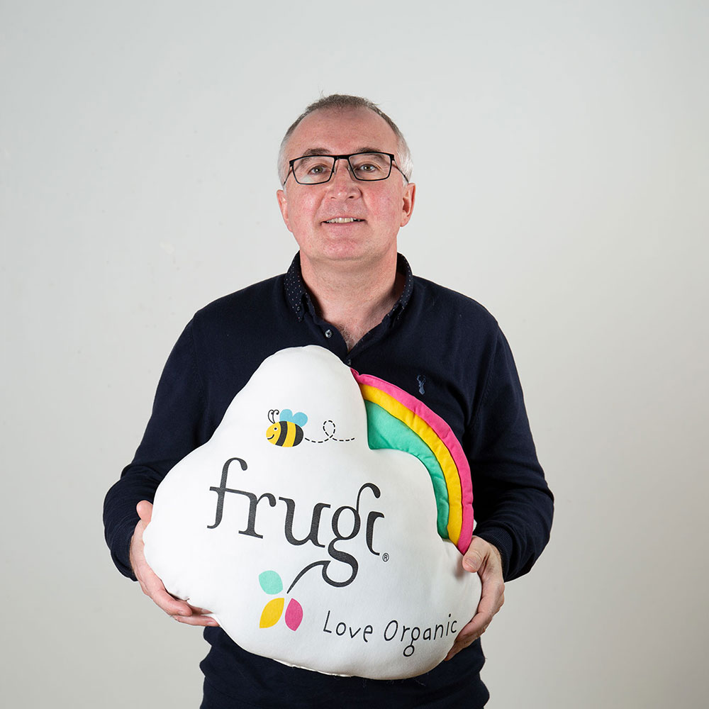 Steve Lucas holding white cloud cushion with Frugi logo