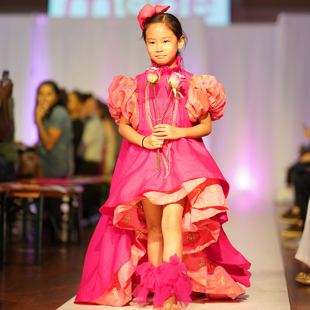 Young girl on the catwalk wearing a red dress