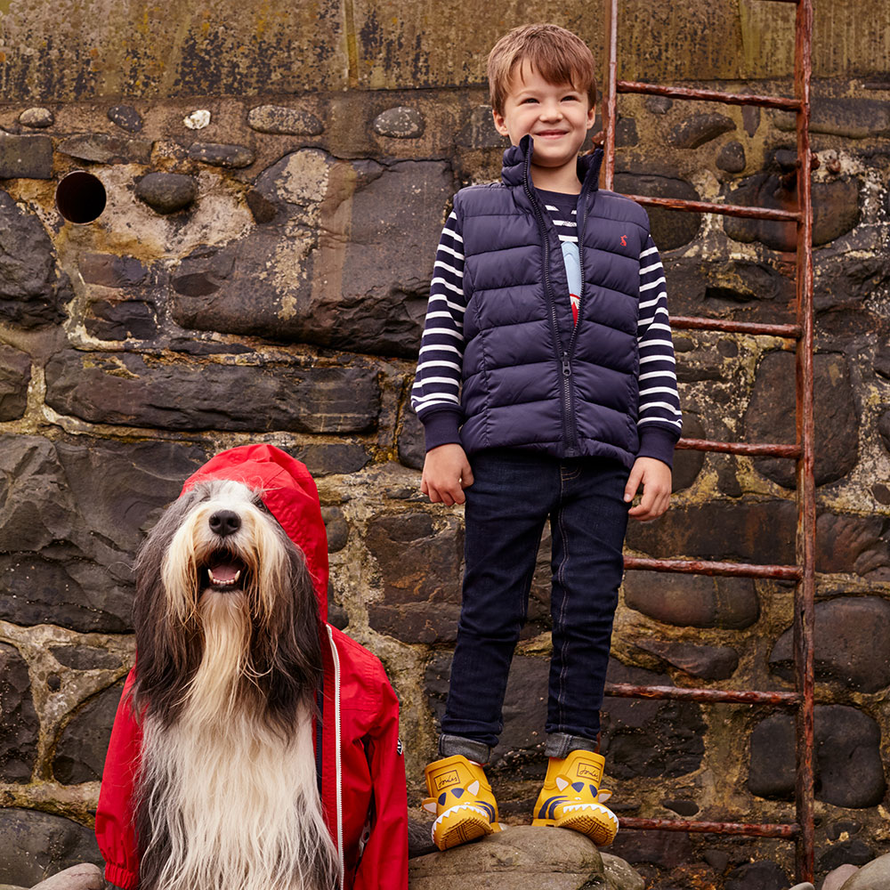 Young boy wearing Joules jacket stood with his dog