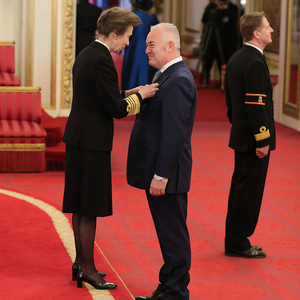 Princess Anne pinning MBE on a mans jacket