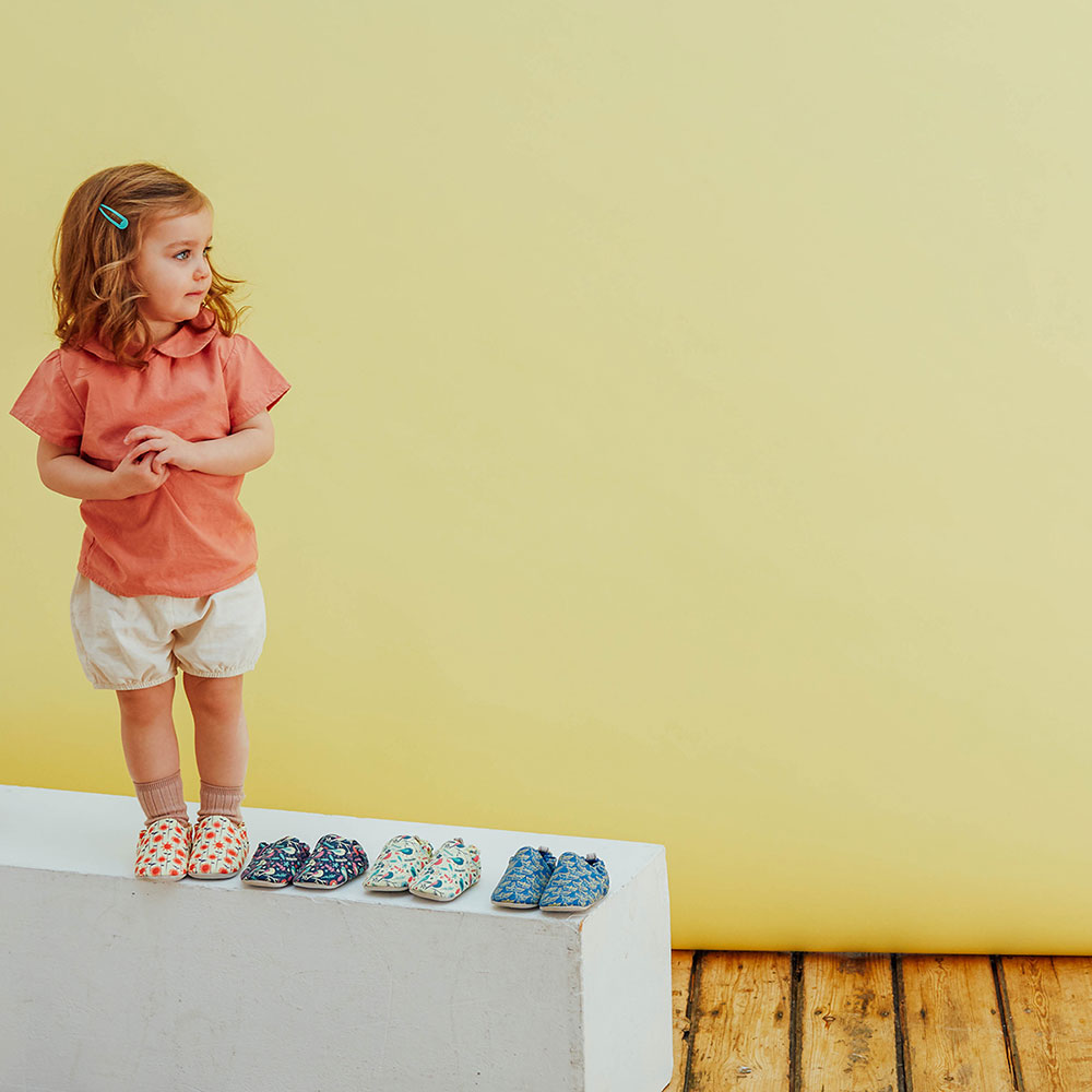 Little girl stood on a white box with Poco Nido baby shoes
