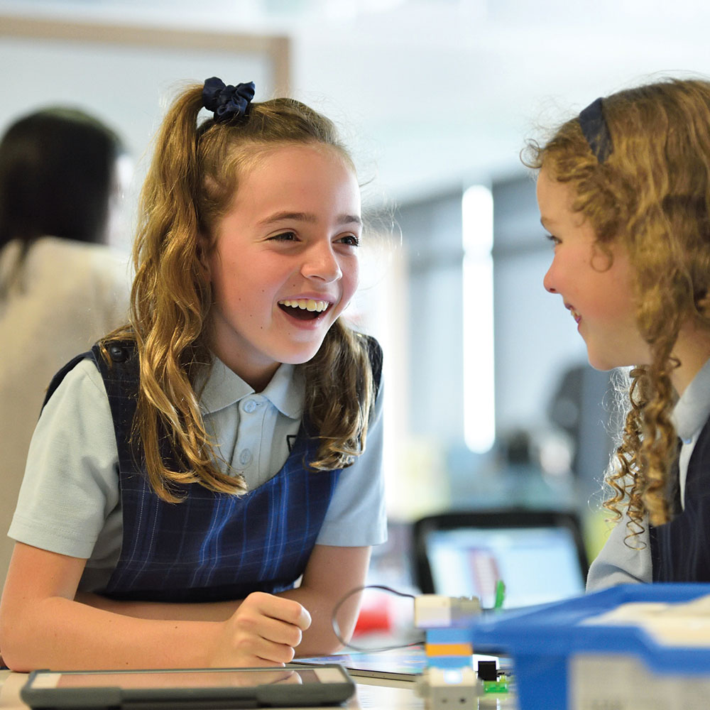 Two young schoolgirls laughing