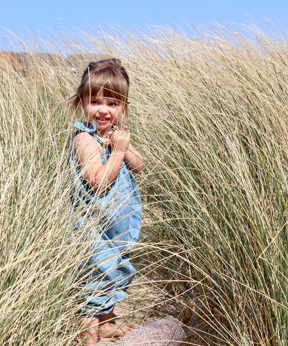 Young girl hiding in long grass at the beach