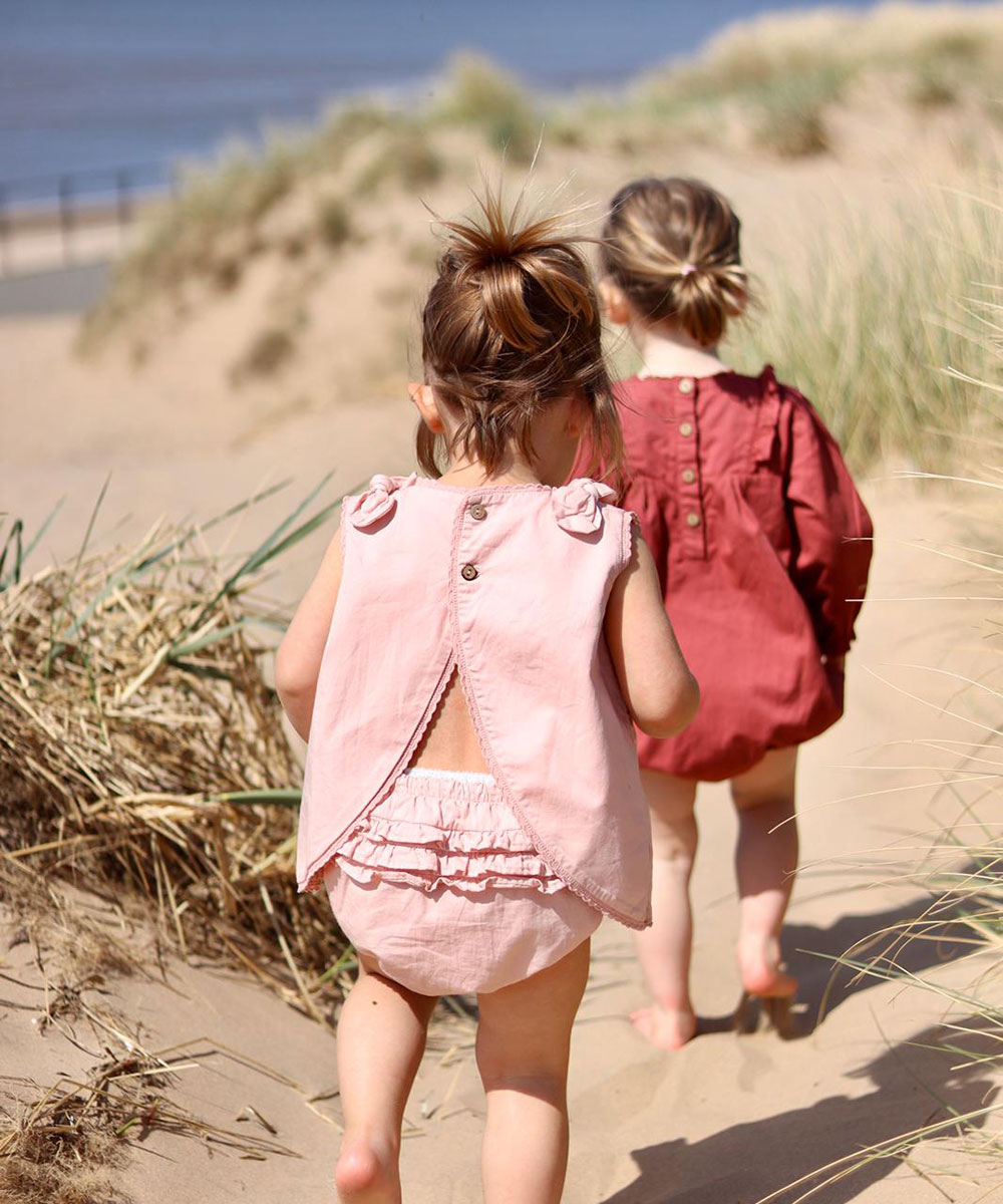 Two young toddlers running to the beach