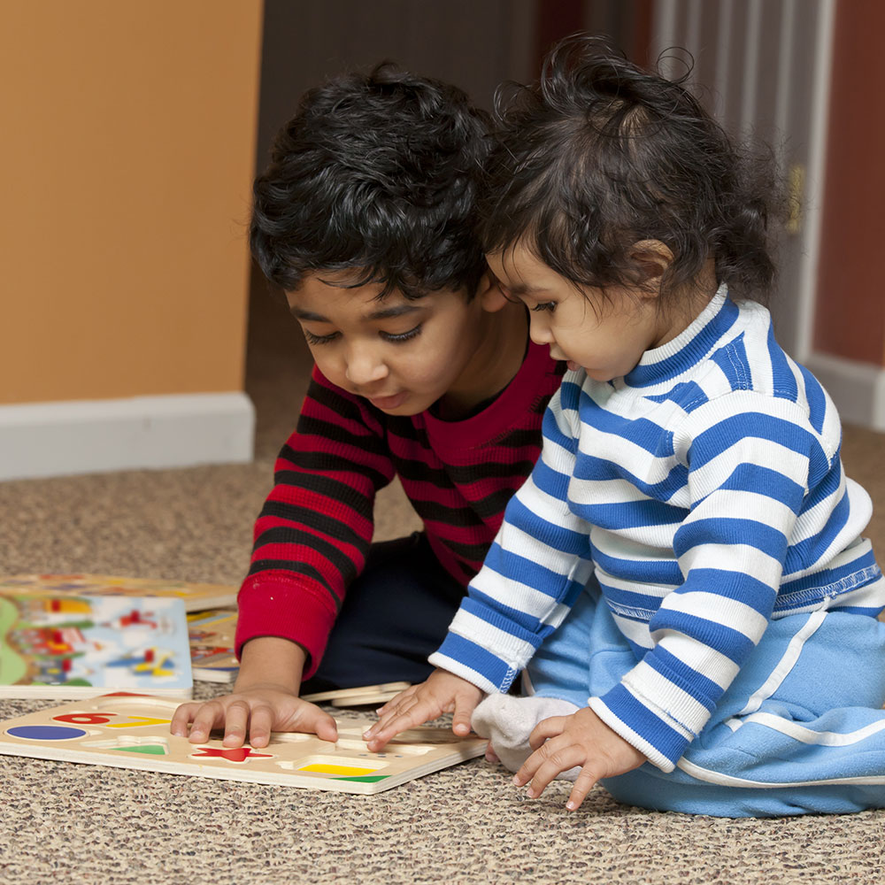 Two young children doing a floor puzzle