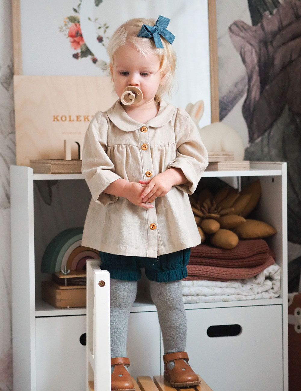 Girl in beige coat with dummy in mouth