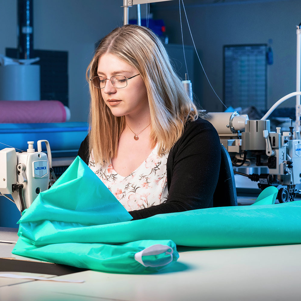 Young woman making NHS gowns on sewing machine