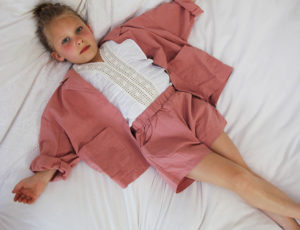 Young girl in pink Pippetta outfit laid on bed
