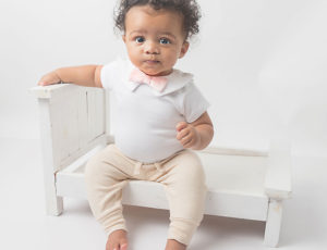 Young toddler sat wearing pink bow tie