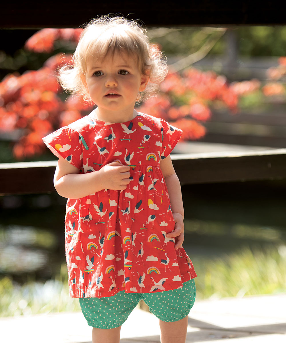 Young girl in red rainbow and flamingo print dress
