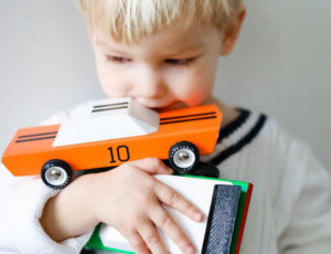 Young boy holding colourful wooden CandyLab toy cars