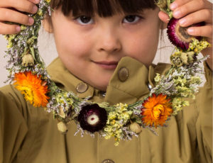 Young girl in green Mini A Ture coat holding a ring of flowers