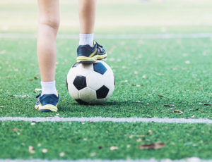 Young boy with foot on top of football - PE and Sport Premium