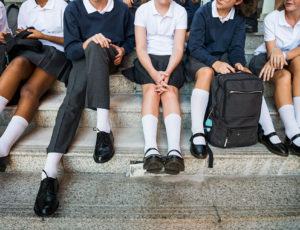 Boys and girls sat on a step wearing school uniforms