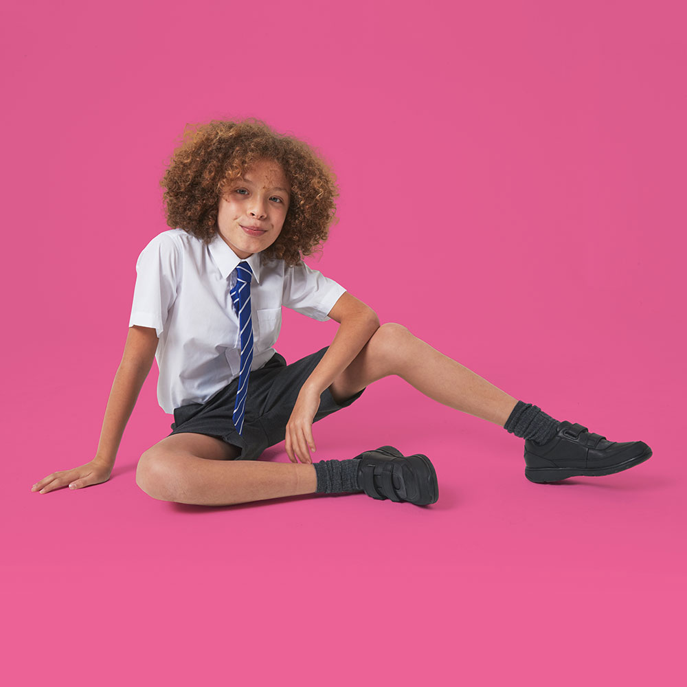 Schoolboy with curly hair against a pink background