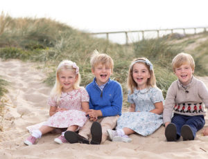 Four children sat in the sand wearing Trotters clothing