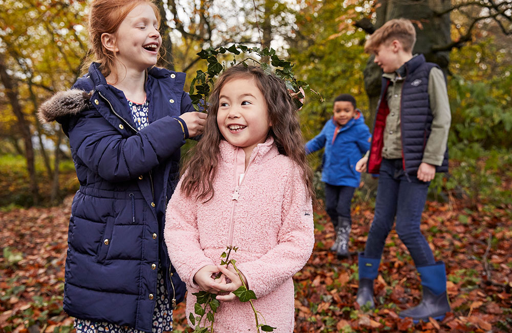 Kids in the woods with Autumn trees wearing Joules clothing