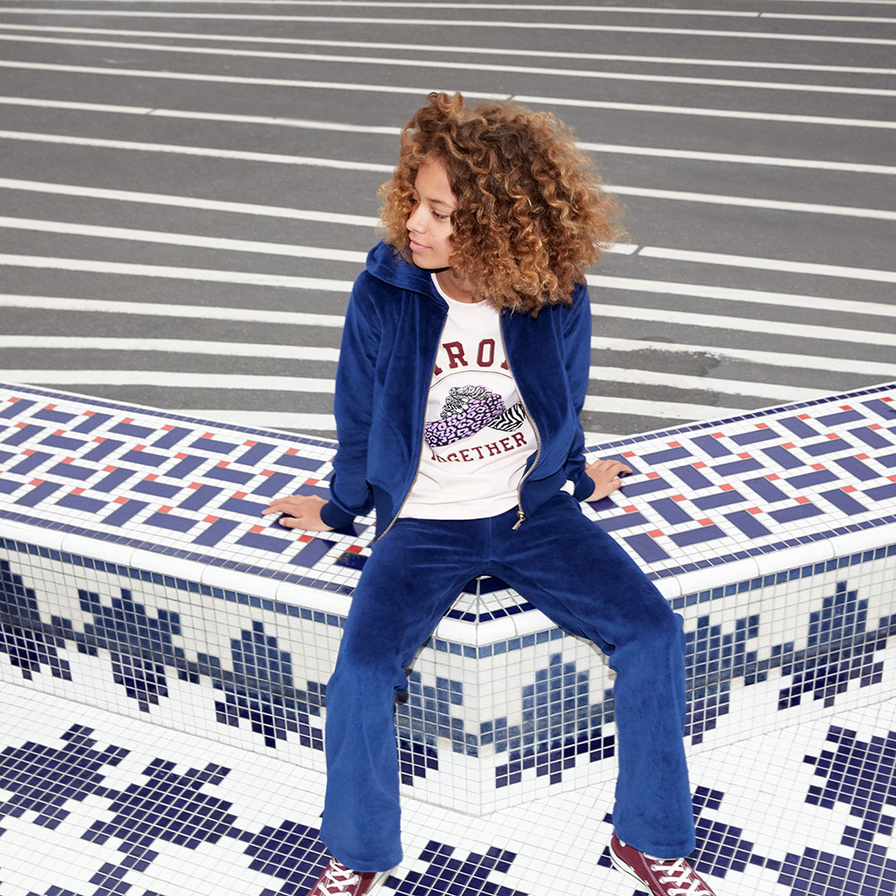 Child in bright blue tracksuit sat on tiled floor - My Wardrobe HQ