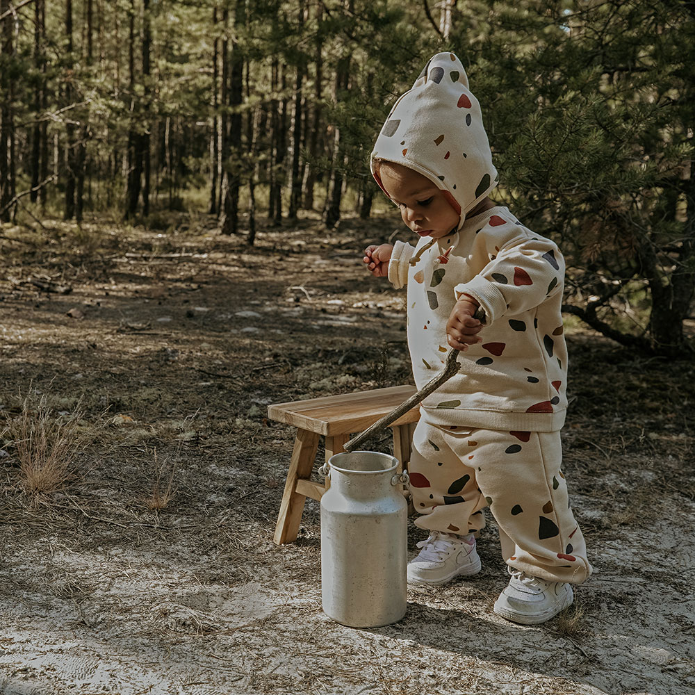 Young boy playing in the woods wearing Organic Zoo beige top and joggers
