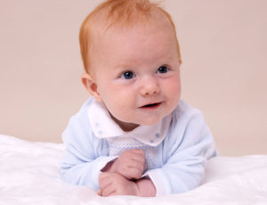 Baby boy laid on his front in blue Pastels & Co babygro