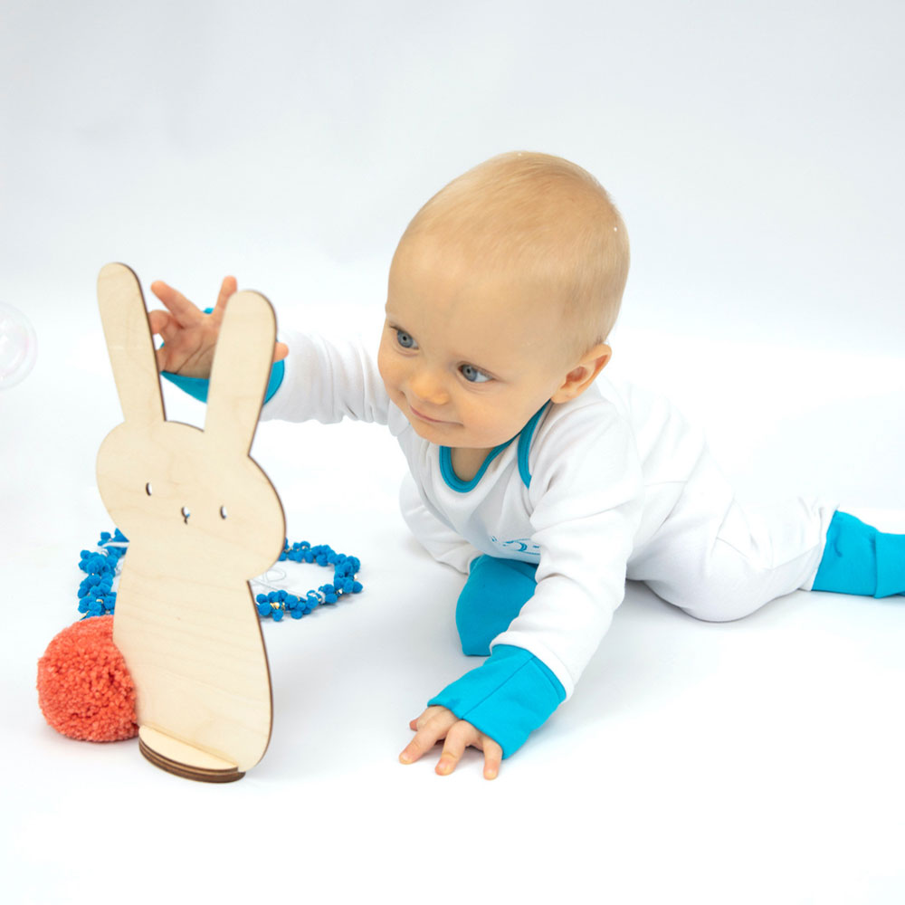 Young baby in white sleep suit with blue cuffs