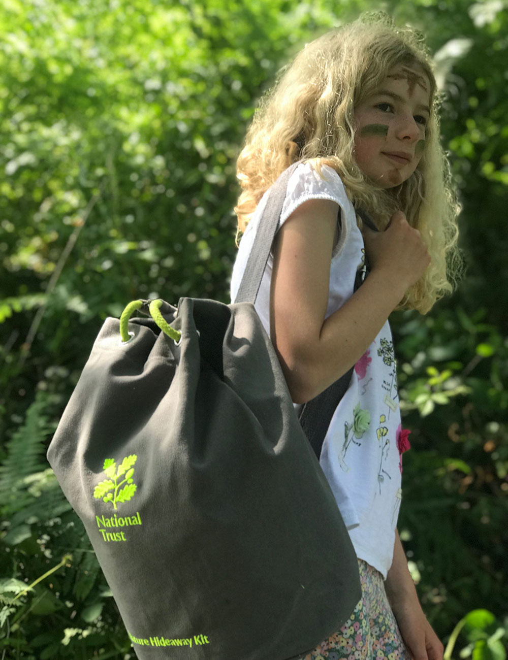 Young girl carrying Den Kit green bag