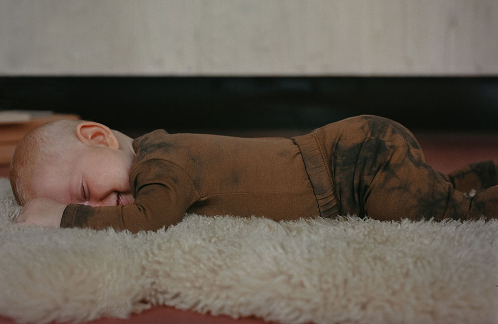 Baby laid face down in dark coloured outfit
