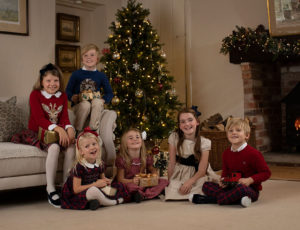 Six children sat next to the fire beside a christmas tree