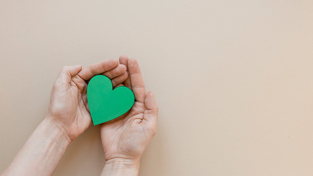 Two hands holding a green heart shaped object