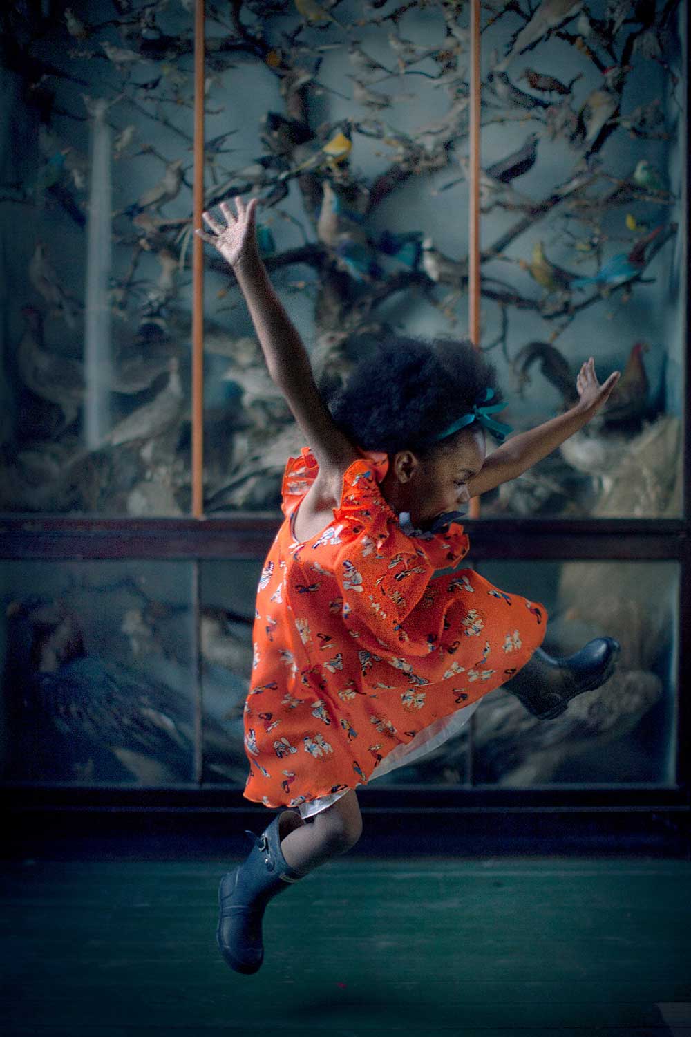 A girl jumping in the air wearing a orange flowery dress