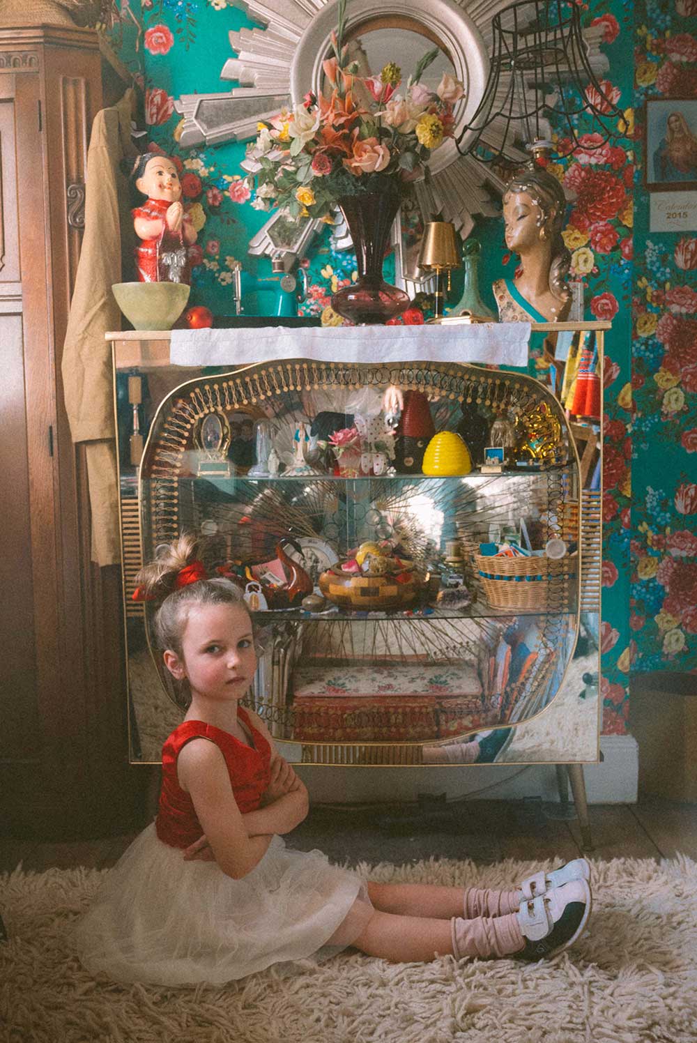 A girl sat on the floor wearing a red and white dress