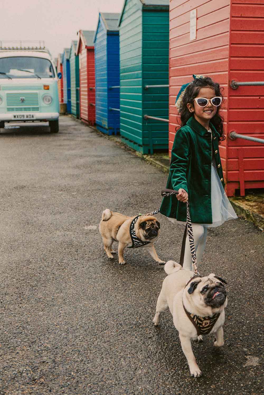 A young girl walking two french bulldogs