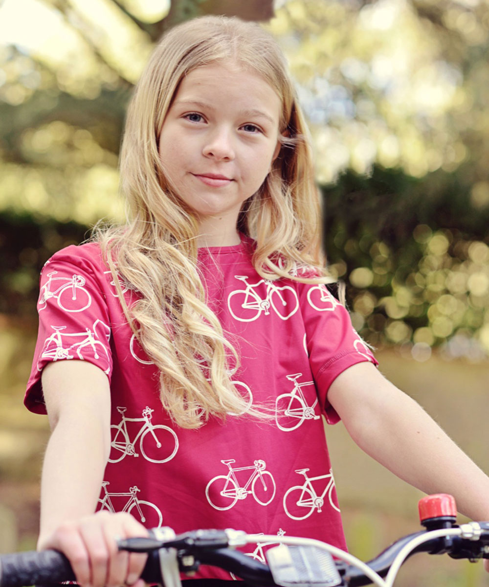 Young girl on bike wearing red Beech T Shirt with bike print
