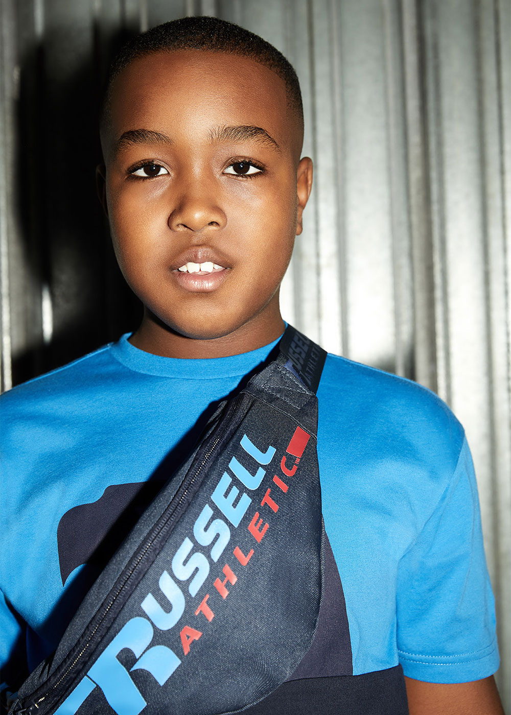 Young boy wearing blue T Shirt with Bag Russell Athletic bag