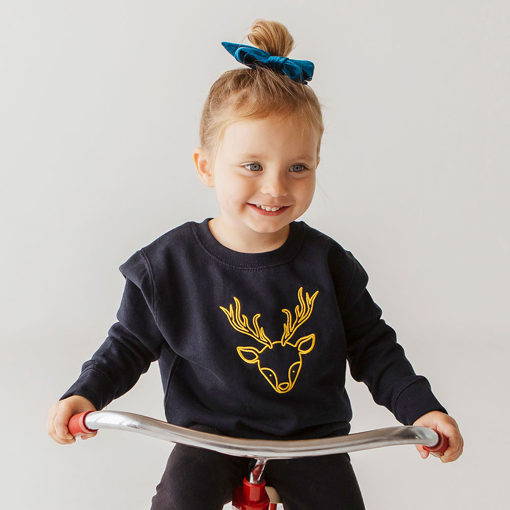 Young girl in Blue jumper with gold reindeer motif