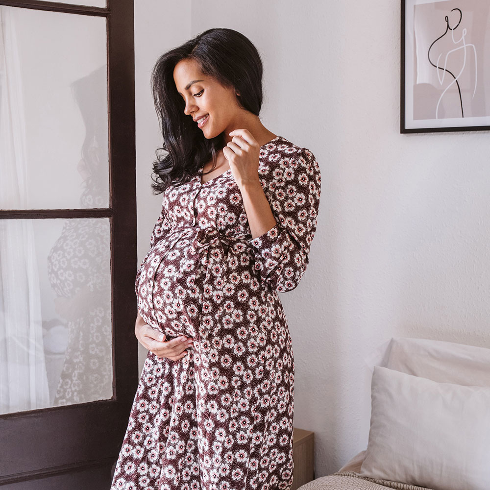 Pregnant lady in floral dress holding bump