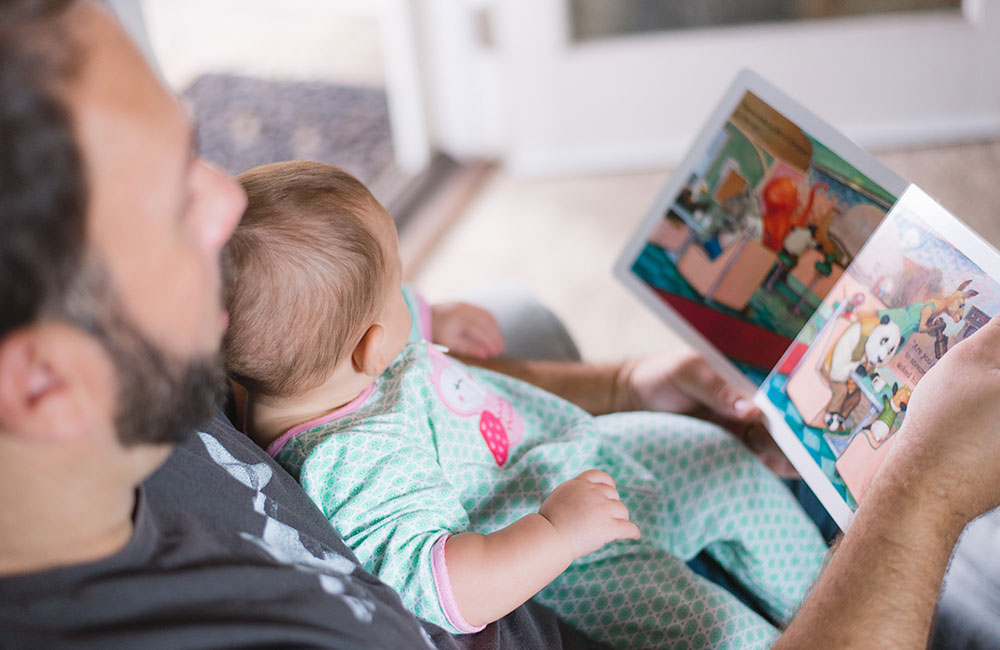 Dad reading a Christmas book to his baby