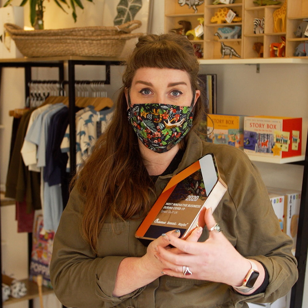 Female Shop owner in face mask holding award