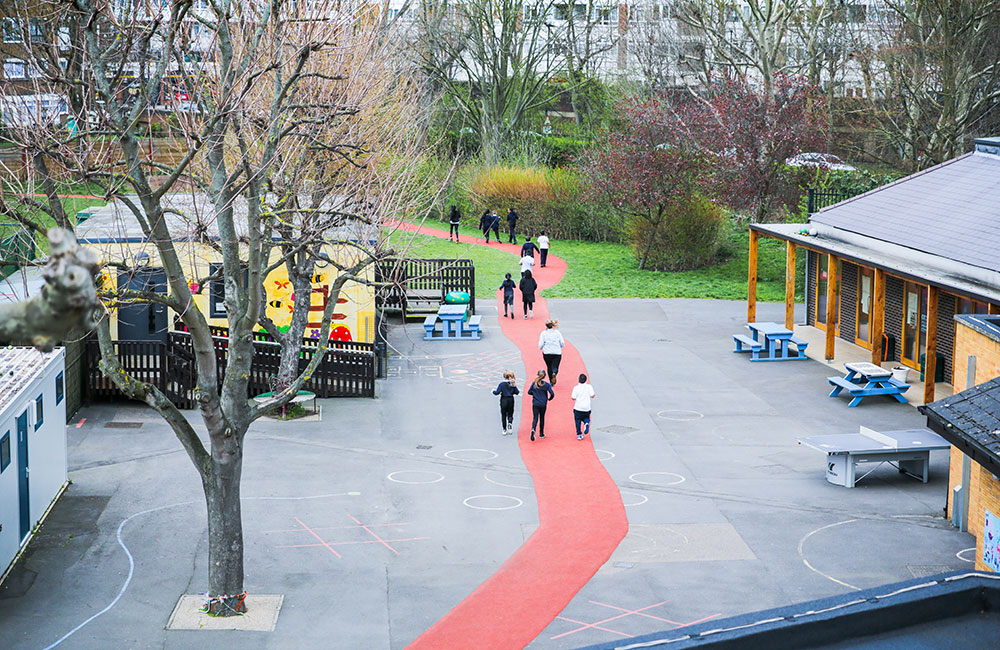 pupils walking along red path in school yard