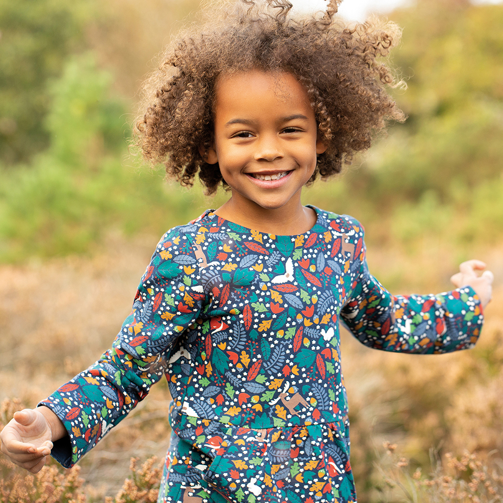 Young girl in blue Frugi dress with Autumnal leaf pattern