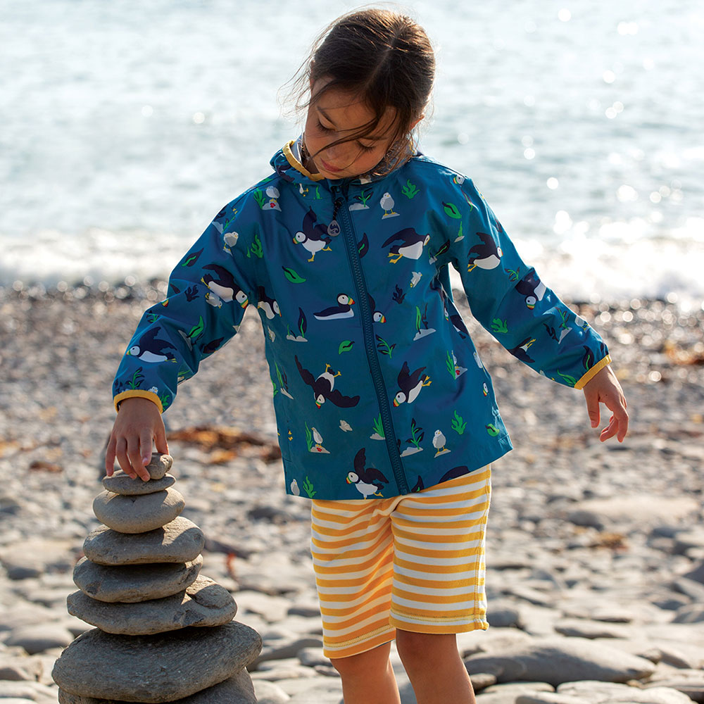 Girl at the beach wearing blue coat with Puffins print