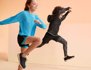 Two young children jumping wearing Goodmove kidswear
