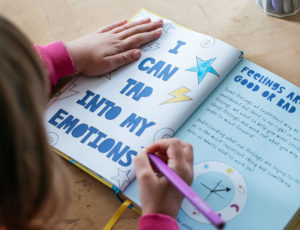 Young girl writing in education book with coloured pen - Top Drawer On Demand
