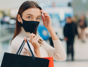 Young lady in black face mask out shopping - Springboard forecasts footfall for reopening of non-essential retail