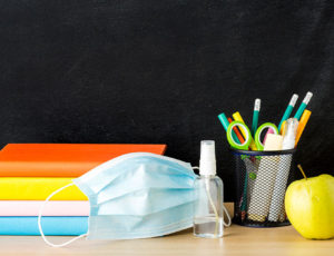 Education image of school books, pens and apple along with facemask - Education Recovery Commissioner